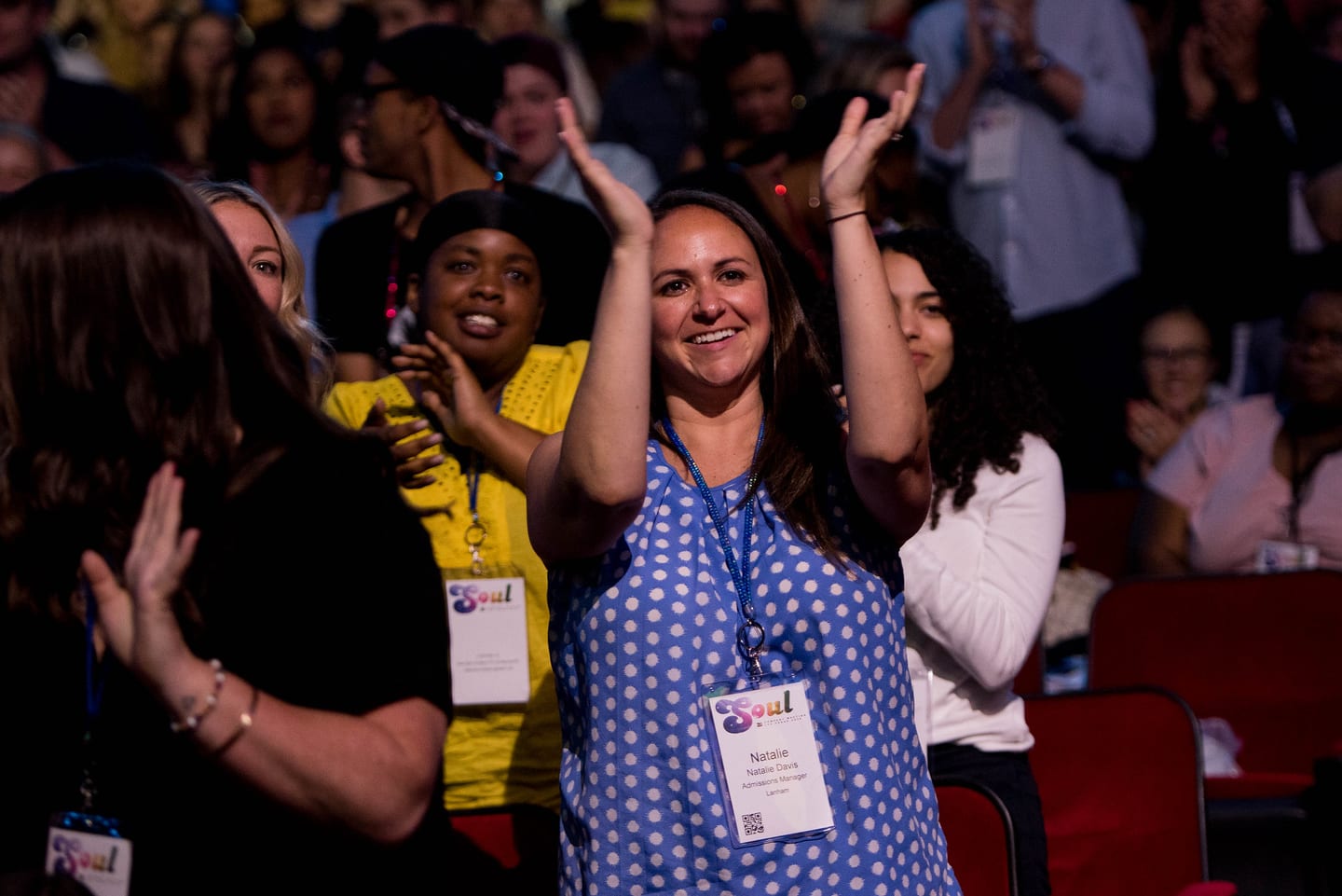 An employee with both arms raised cheering among the seated crowd