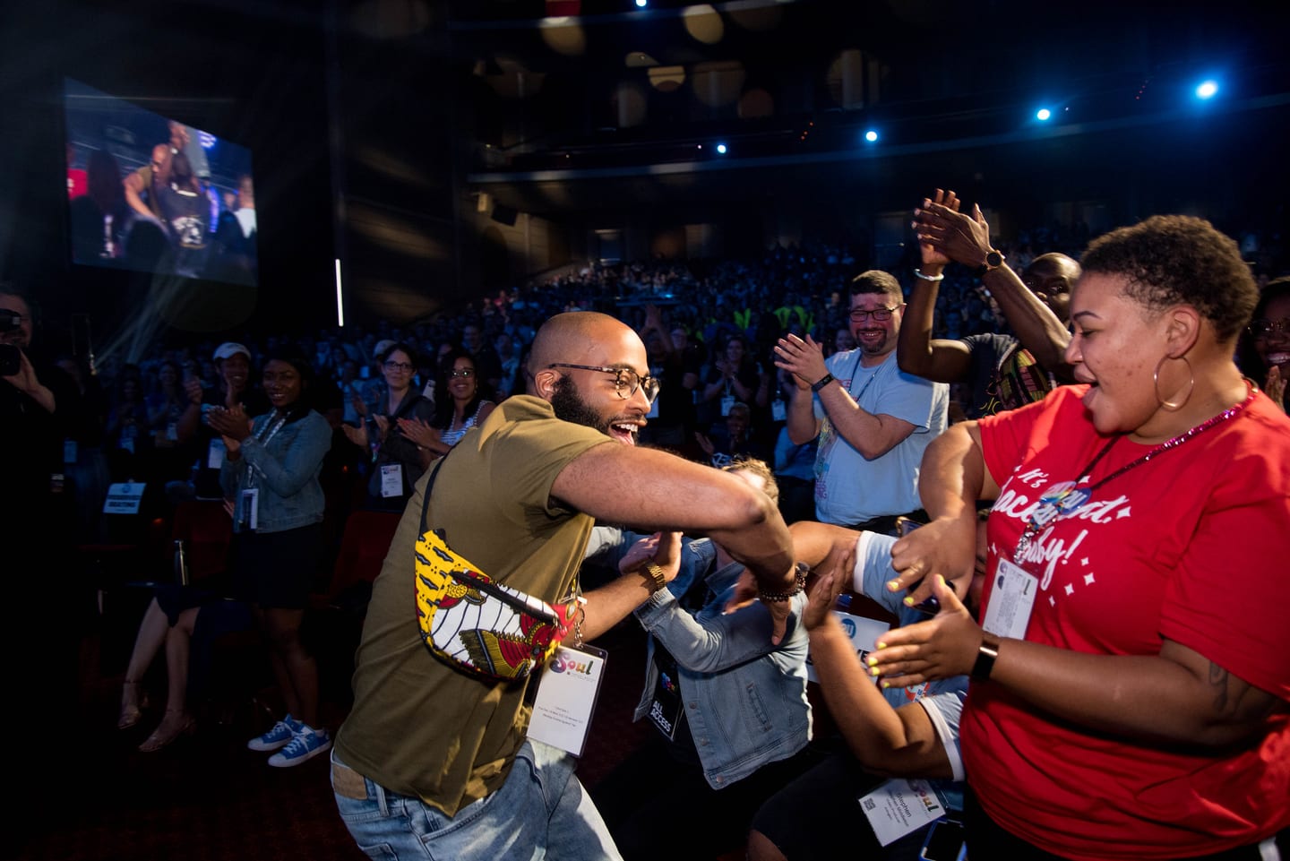 Two employees embracing and cheering in the aisle during a general session
