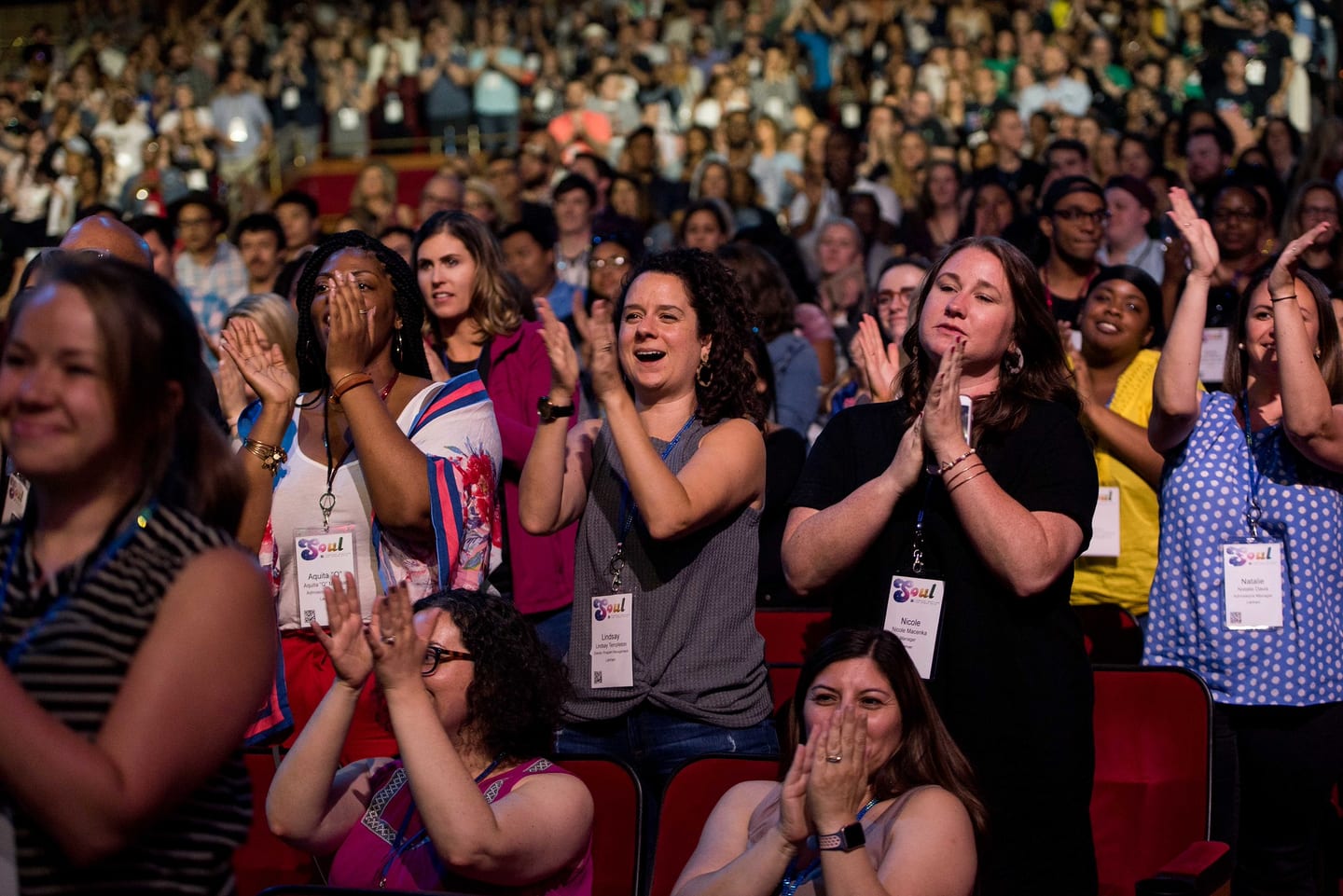 A packed section of the audience clapping and laughing during a general session