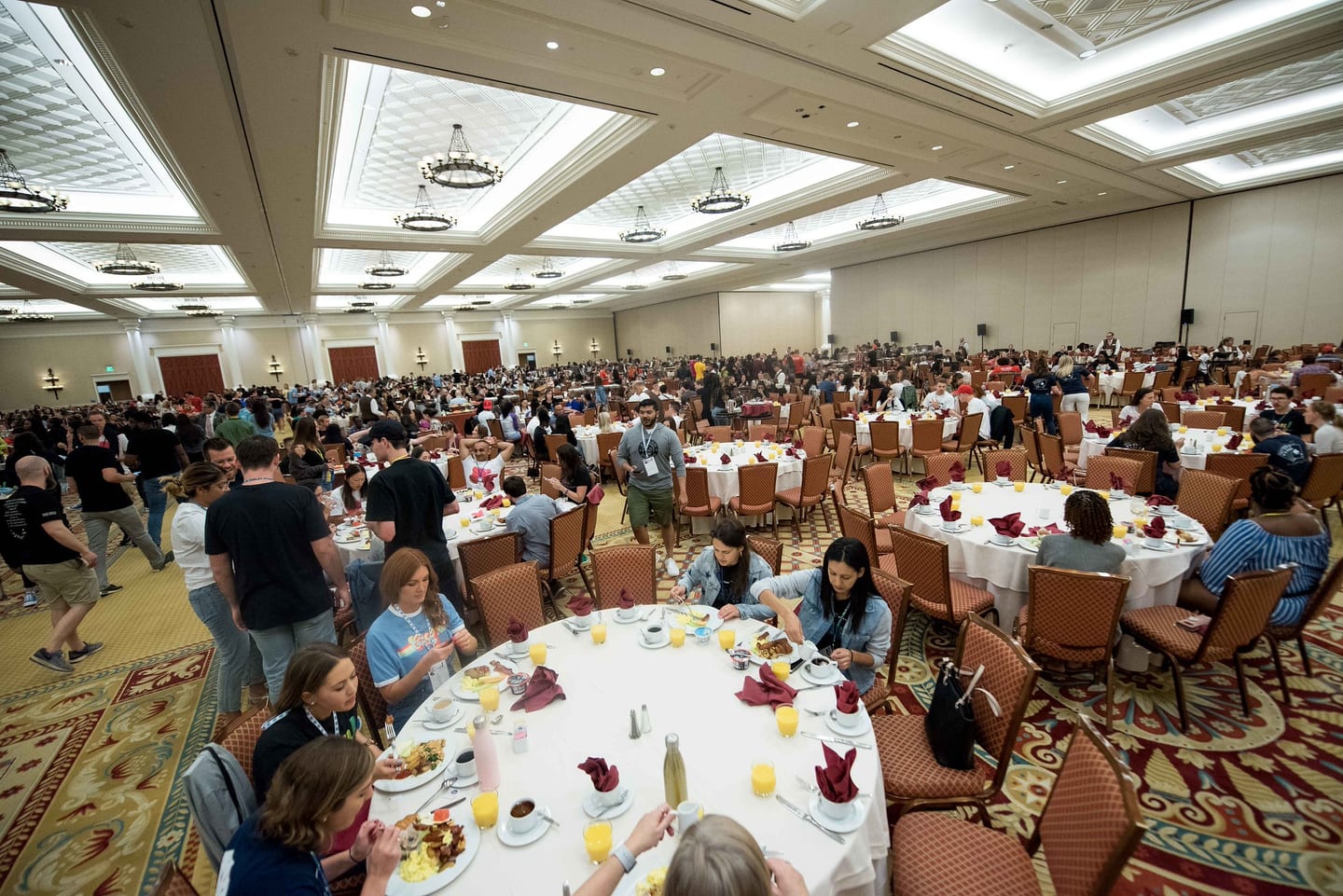 A wide view of a Caesars Palace ballroom set for breakfast with employees filling the round tables