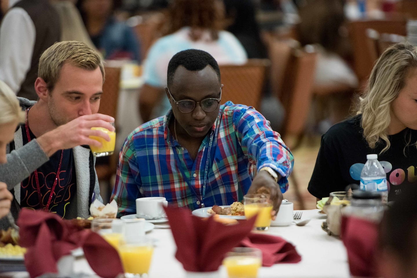 An employee drinking juice at a busy breakfast table