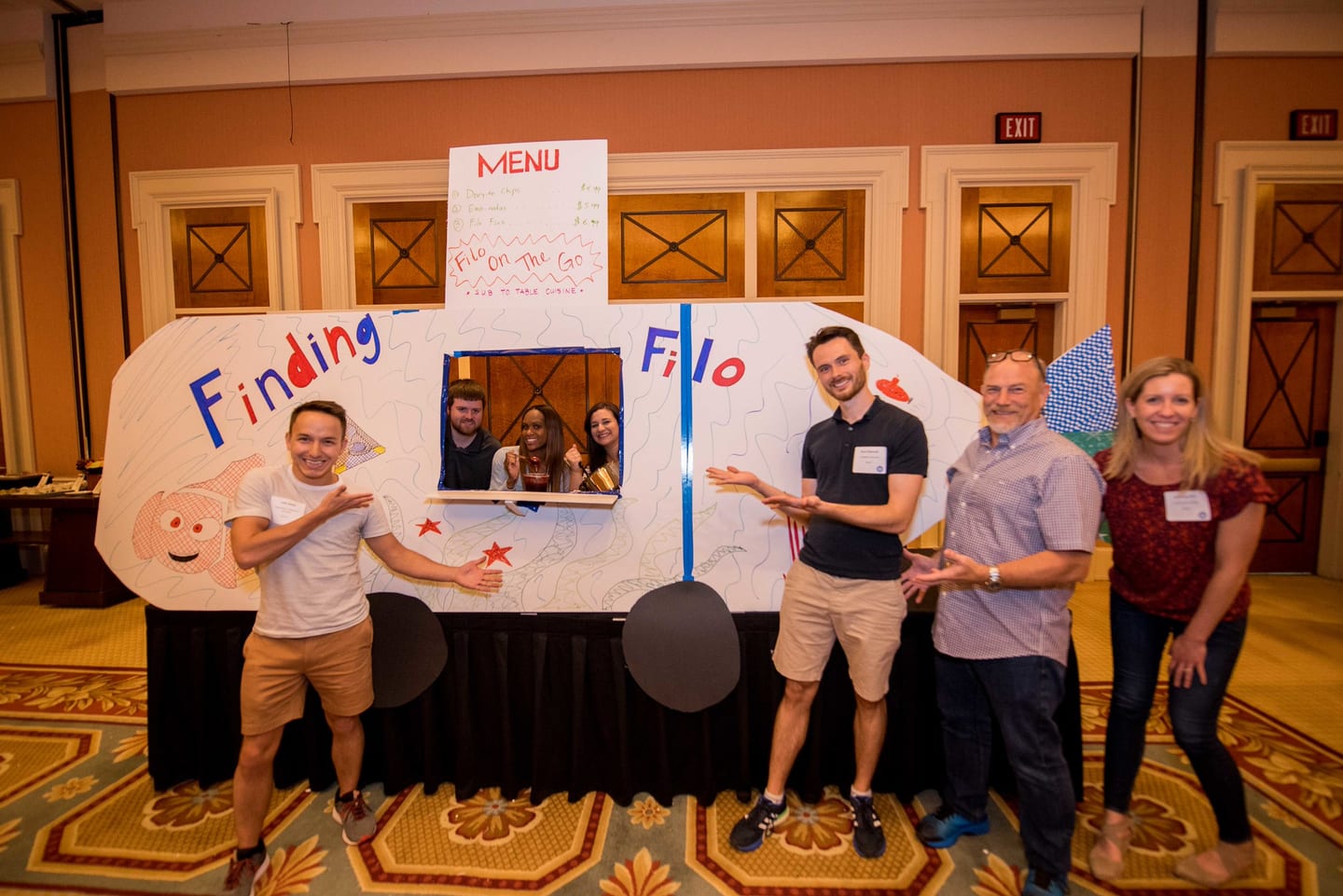 Four employees standing behind a hand-made project booth in a Caesars Palace ballroom
