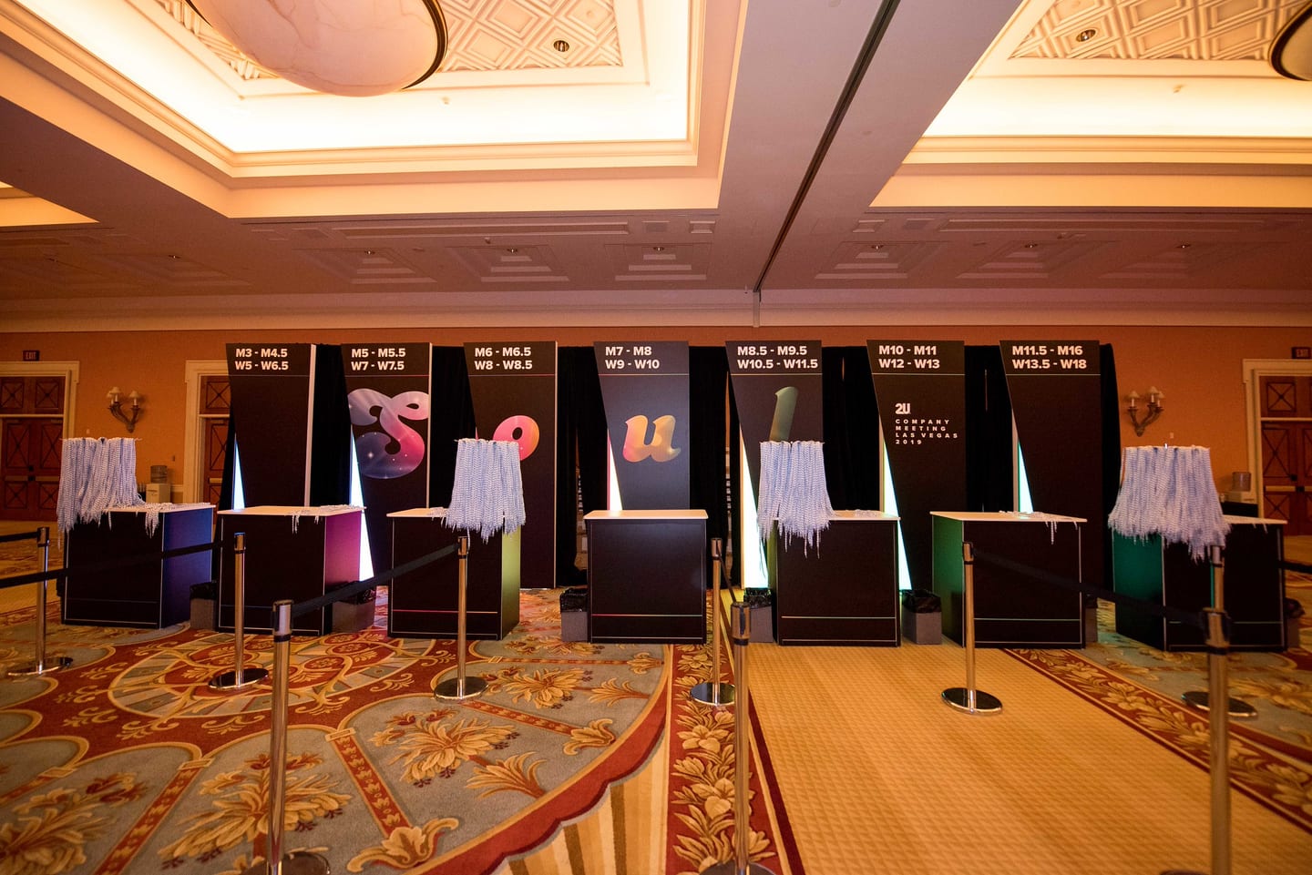 A row of wayfinding boards listing breakout rooms across a Caesars Palace foyer