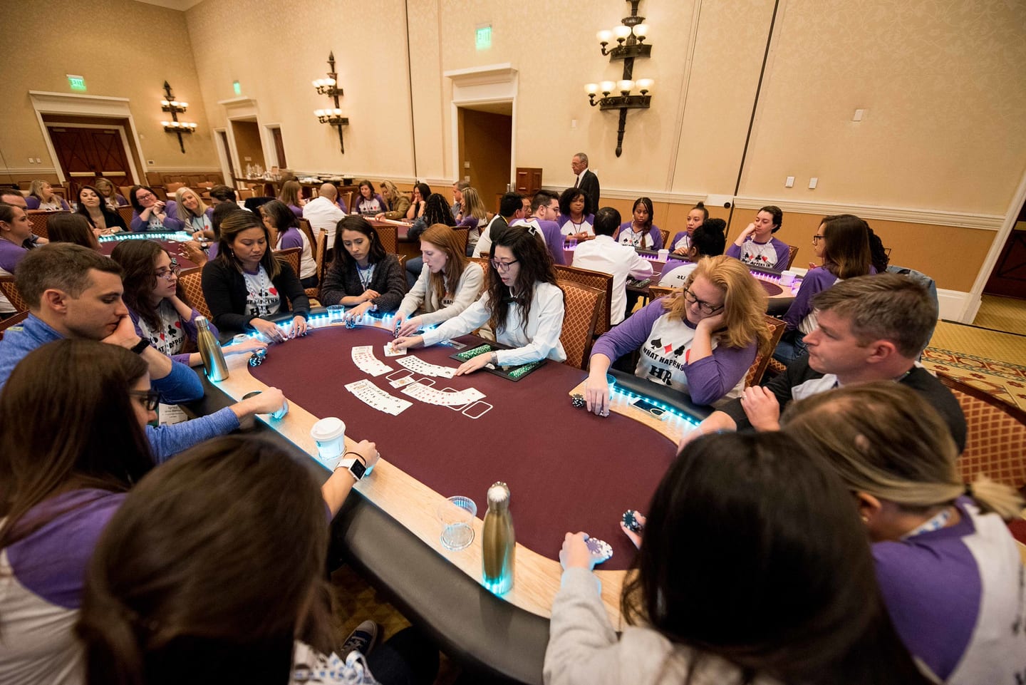 Employees seated around a long table in a breakout workshop, papers and laptops in front of them