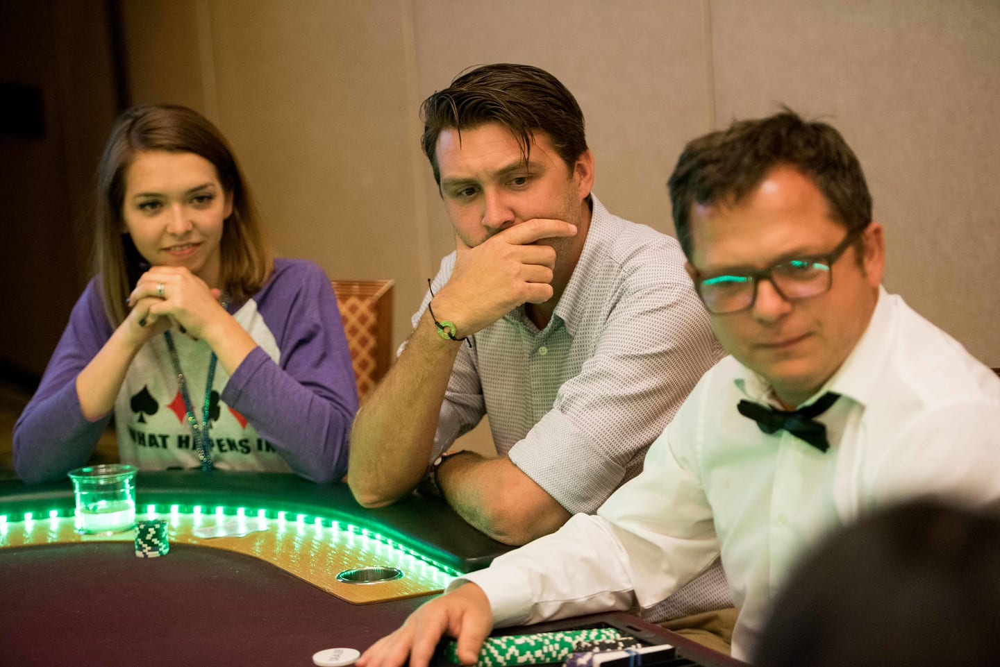 Three employees playing at a lit casino table during the evening activation