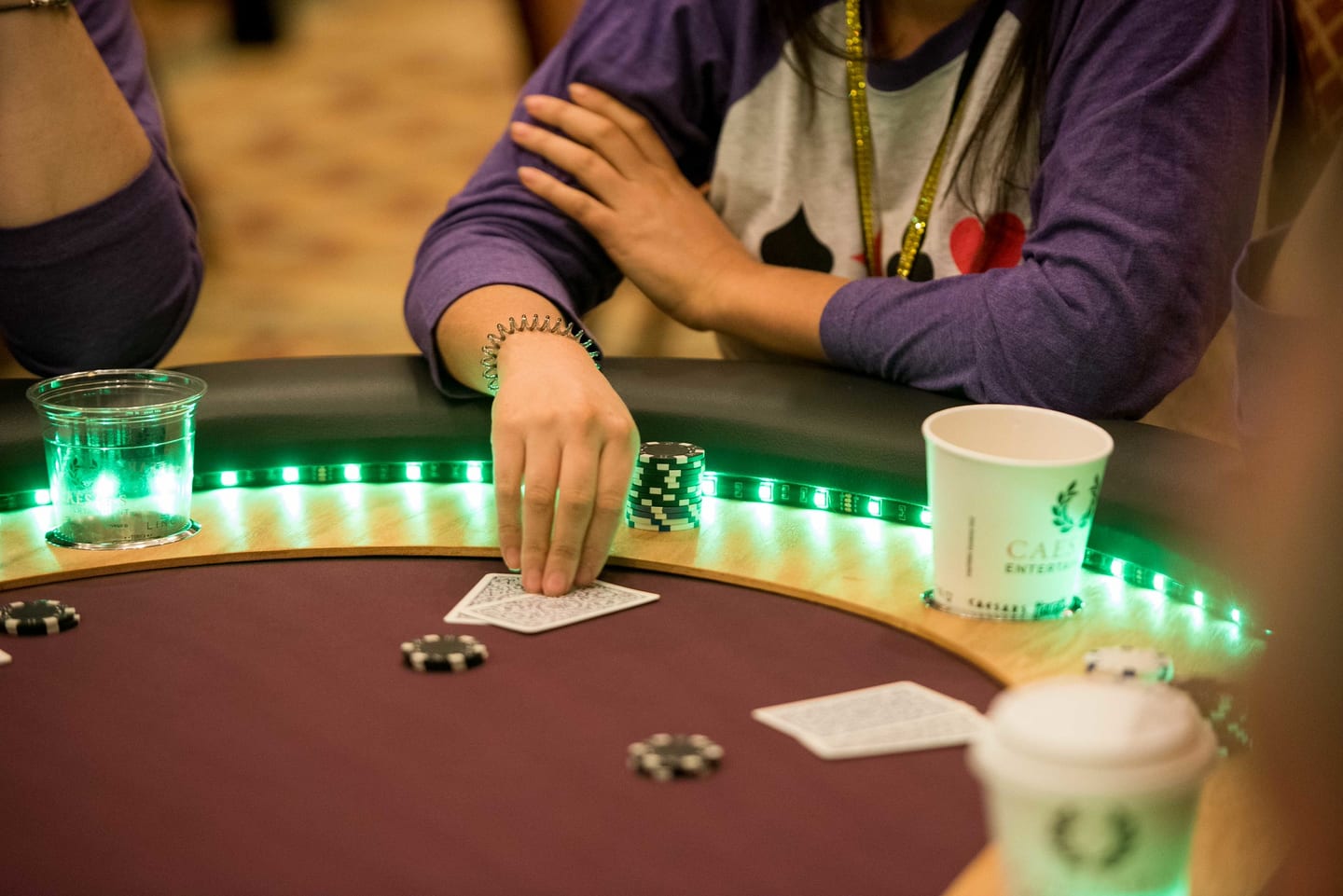 A dealer's hands on a green-lit casino table with cards and chips at an evening activation