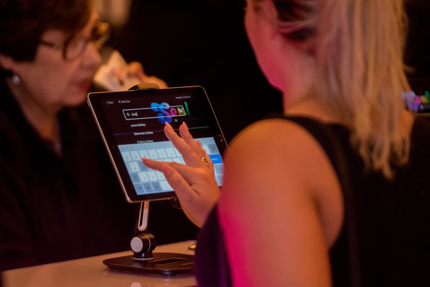 An attendee tapping a check-in tablet at the registration desk