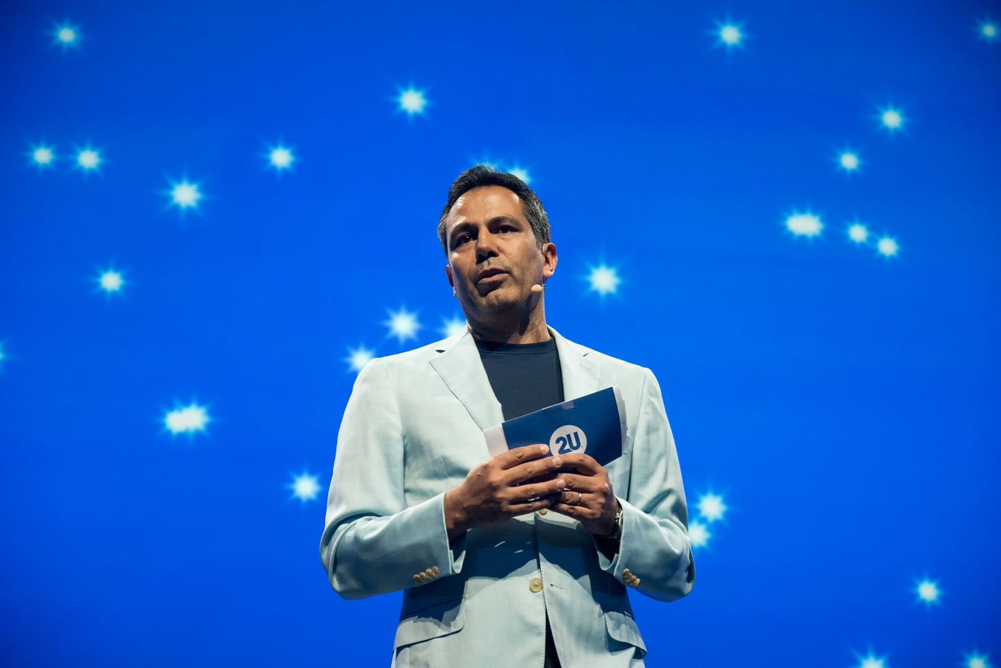 2U co-founder Chip Paucek speaking on the Colosseum stage in front of a blue starfield screen