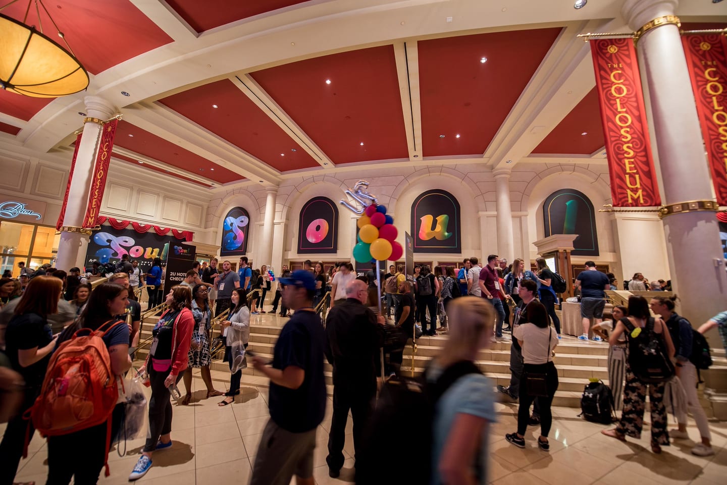 A wide view of the Colosseum lobby with employees gathering under the venue's red columns