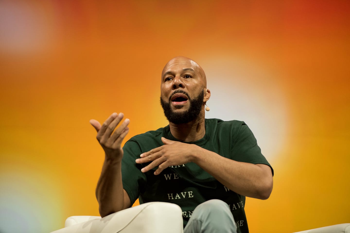 The musician and actor Common speaking with his hands during a seated fireside on the Colosseum stage