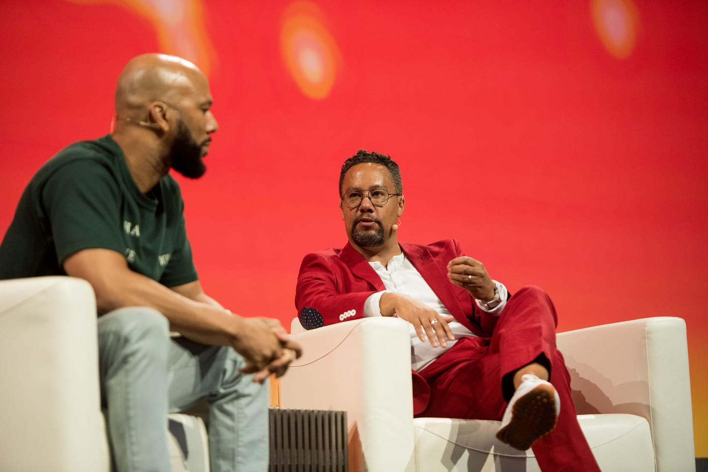 Common in conversation with an interviewer in a red suit, both seated in white armchairs on the Colosseum stage