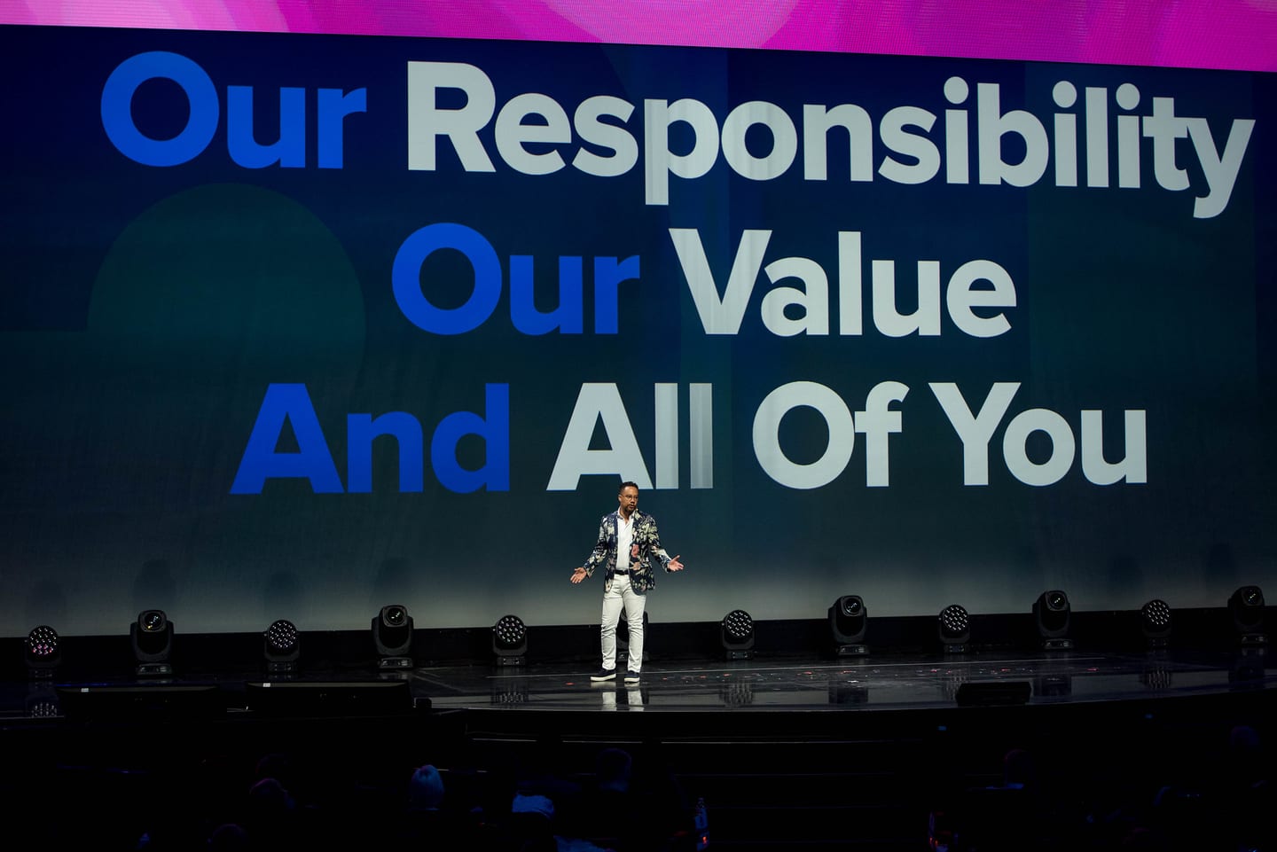 A speaker on a large main stage before a giant screen reading “Our Responsibility, Our Value, And All Of You” at the 2U conference in Las Vegas