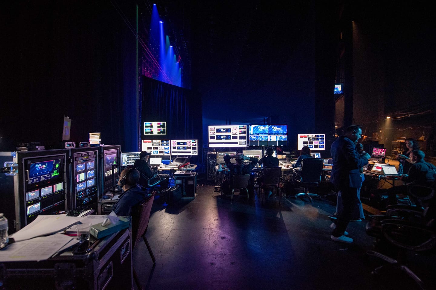 The production control position at the back of the Colosseum, monitors and desks lit blue