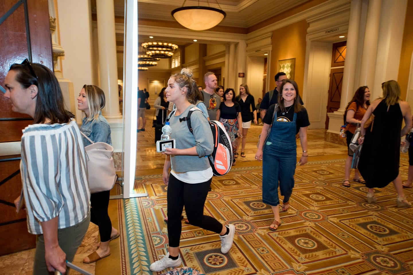 Employees walking a patterned hotel corridor between breakout sessions