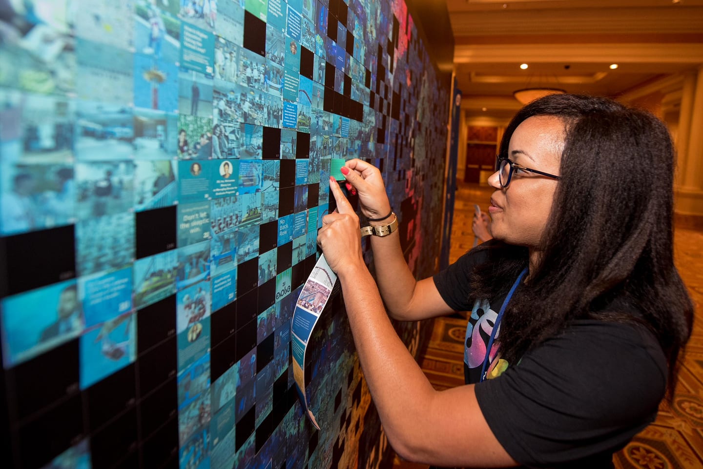 An employee pressing a photo tile into the mosaic wall installation