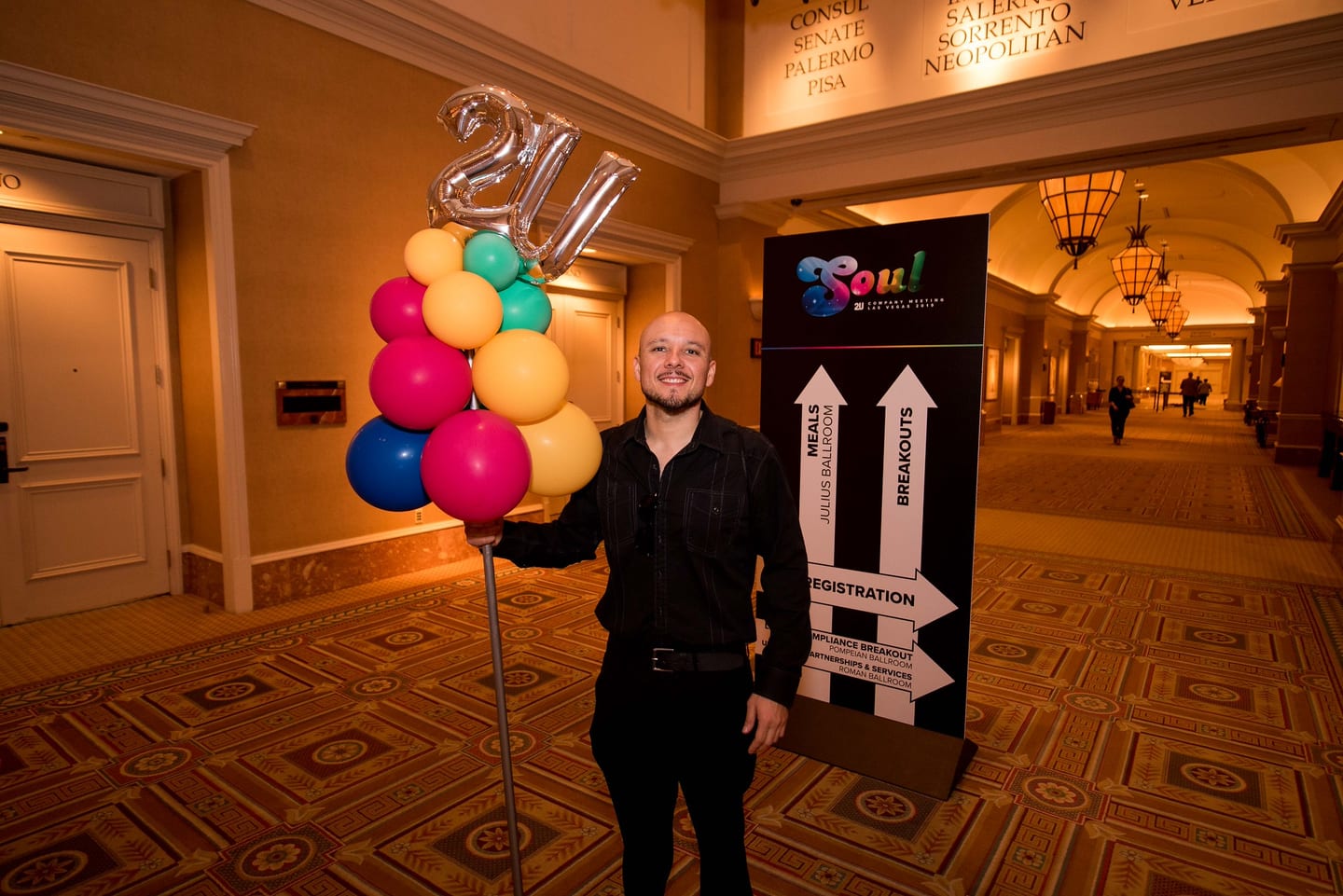 A staffer beside 2U balloons and SOUL wayfinding signage at the registration entrance