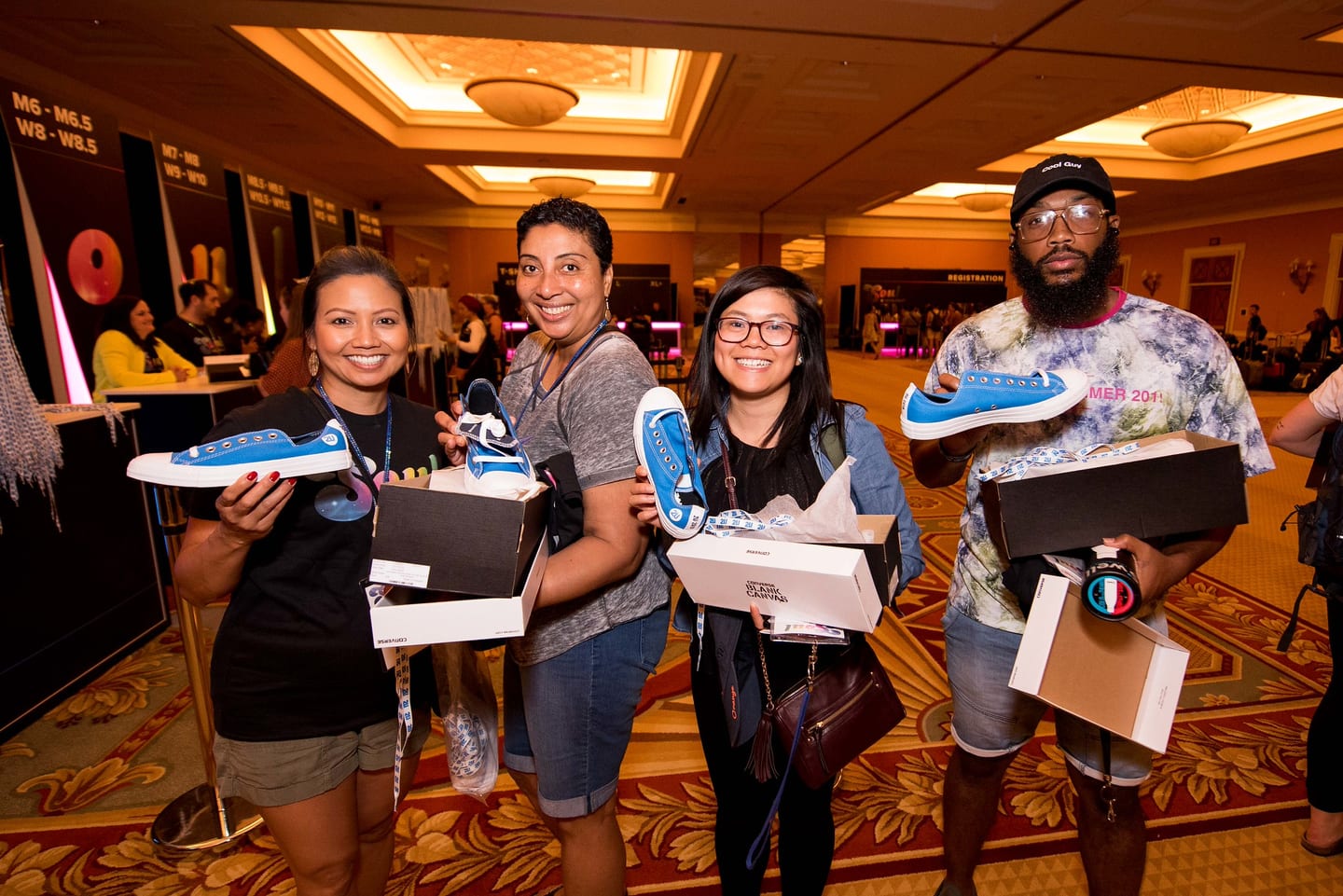 Four employees holding open sneaker boxes at the 2U company meeting