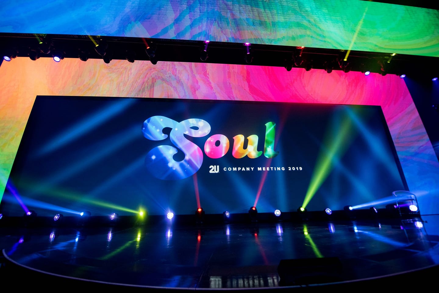 The wide SOUL stage screen at the Colosseum lit magenta and green with light beams across an empty house
