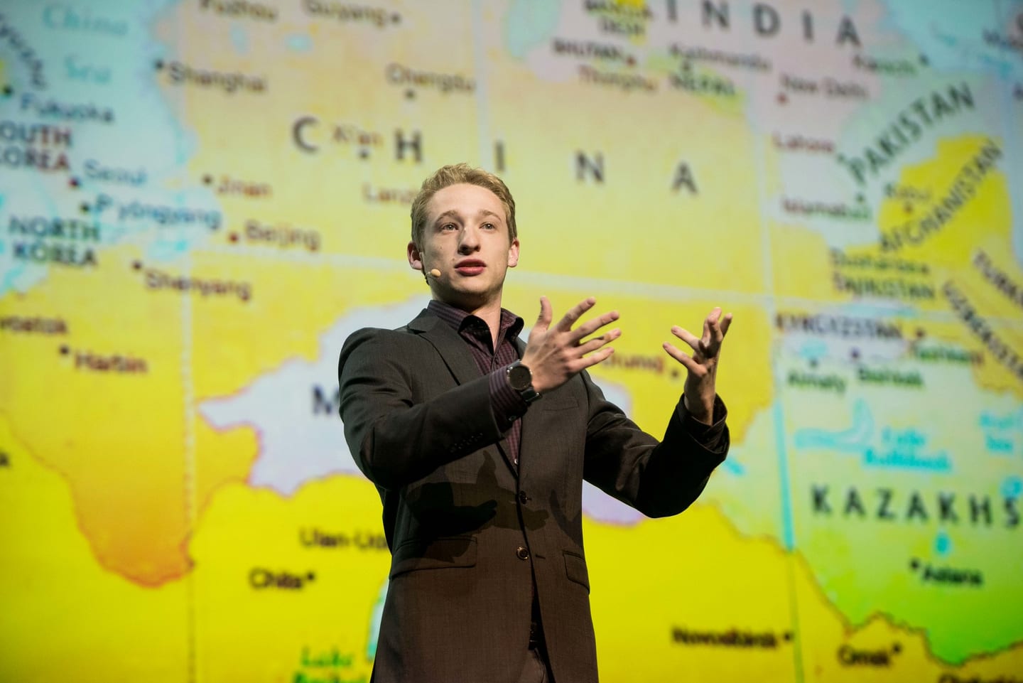 A speaker presenting in front of a full-width world map showing India and China