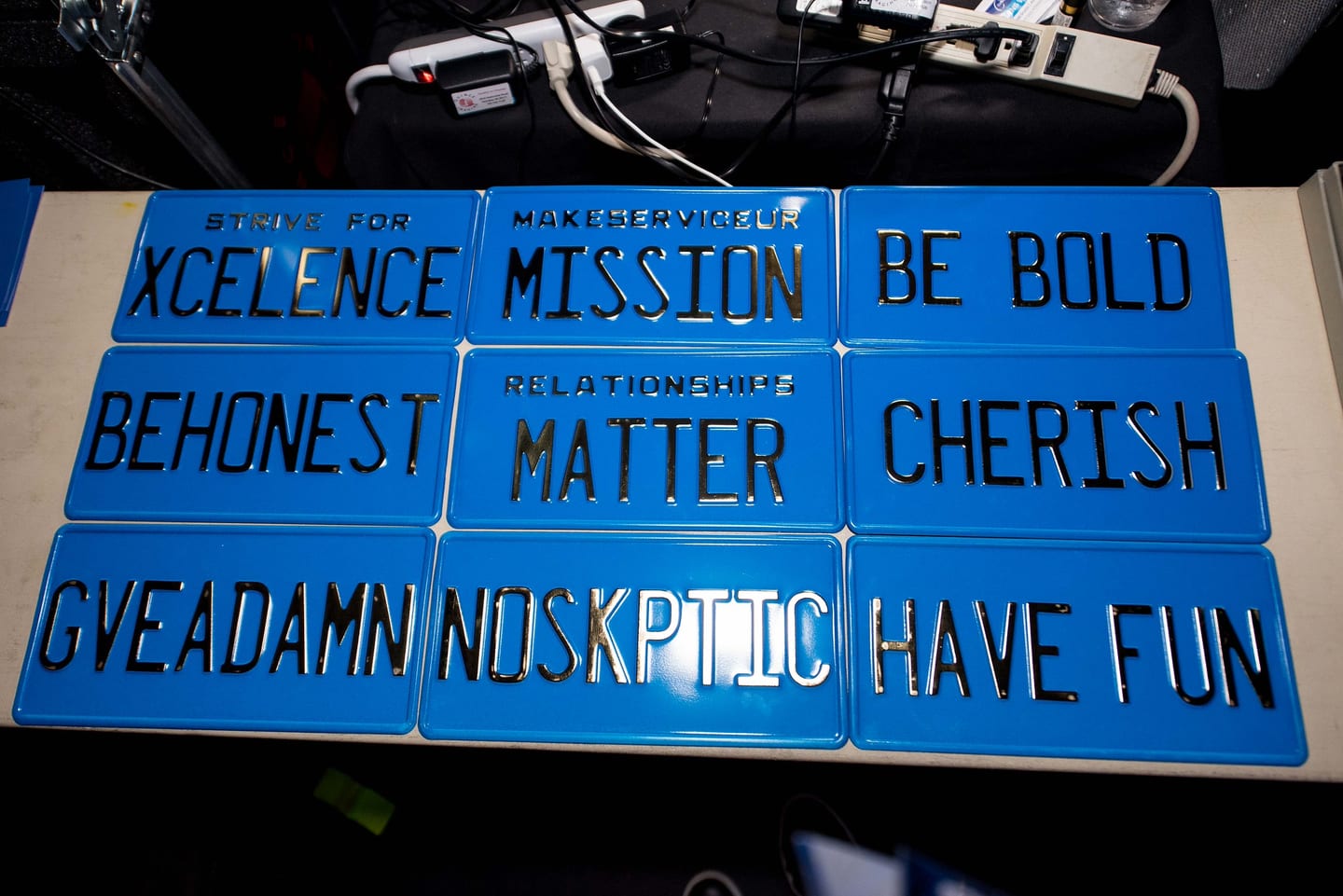 A tray of blue licence plates printed with the company values including BE BOLD, CHERISH and HAVE FUN