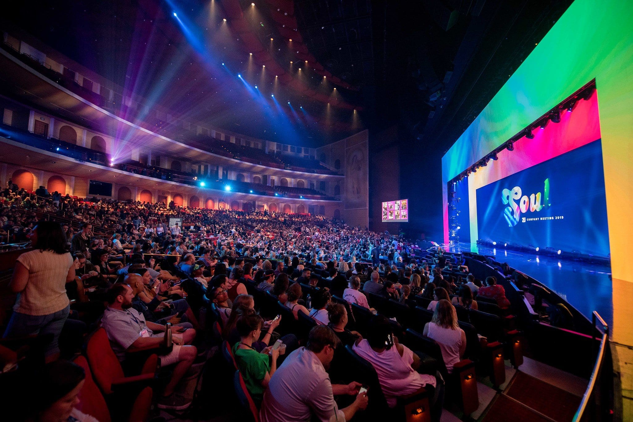 Massive conference main stage with colorful screens and full audience