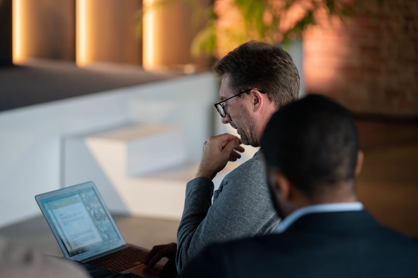 An attendee working on a laptop while talking with another guest at the Automotive News Congress: Los Angeles, City Market Social House