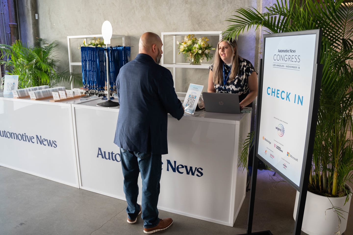 An attendee checking in at the Automotive News branded registration desk beneath a Check In sign at the Automotive News Congress: Los Angeles, City Market Social House