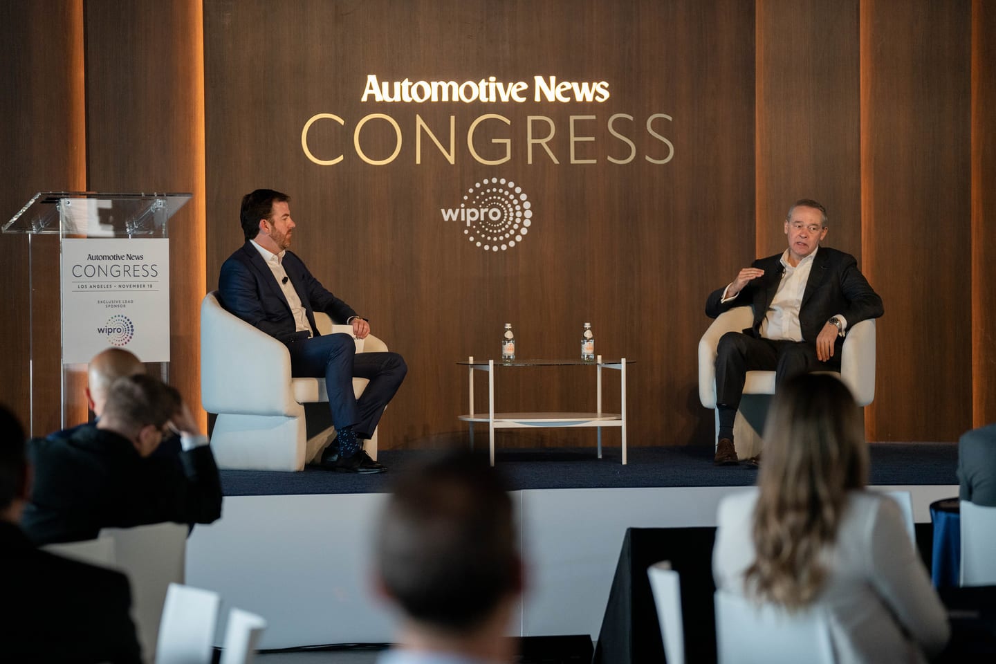 A fireside conversation on stage seen wide from the audience floor at the Automotive News Congress: Los Angeles, City Market Social House