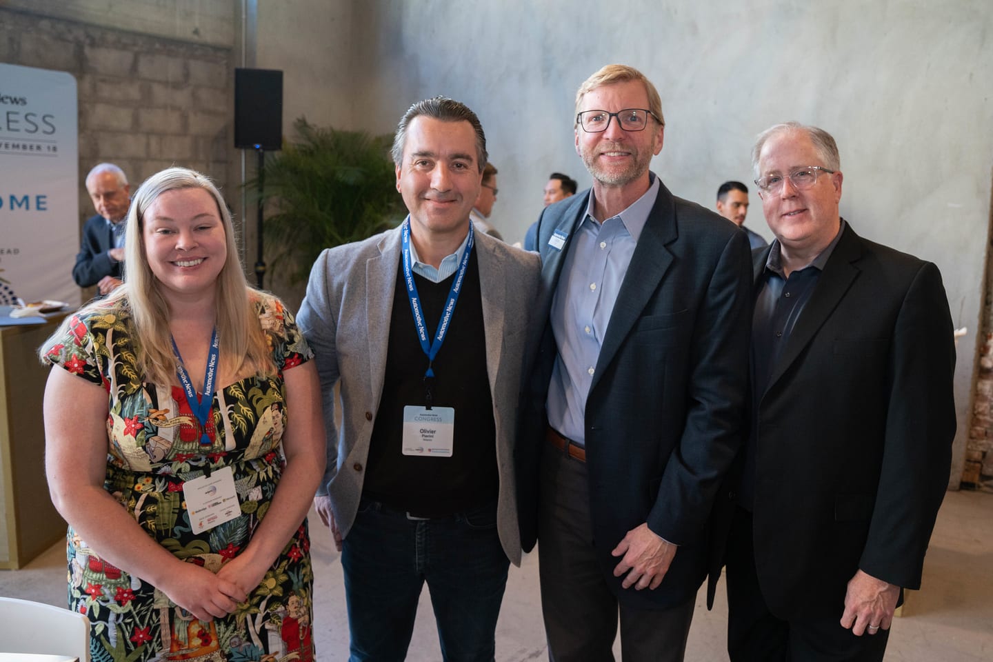 Four attendees posing together in front of the Welcome wall at the Automotive News Congress: Los Angeles, City Market Social House