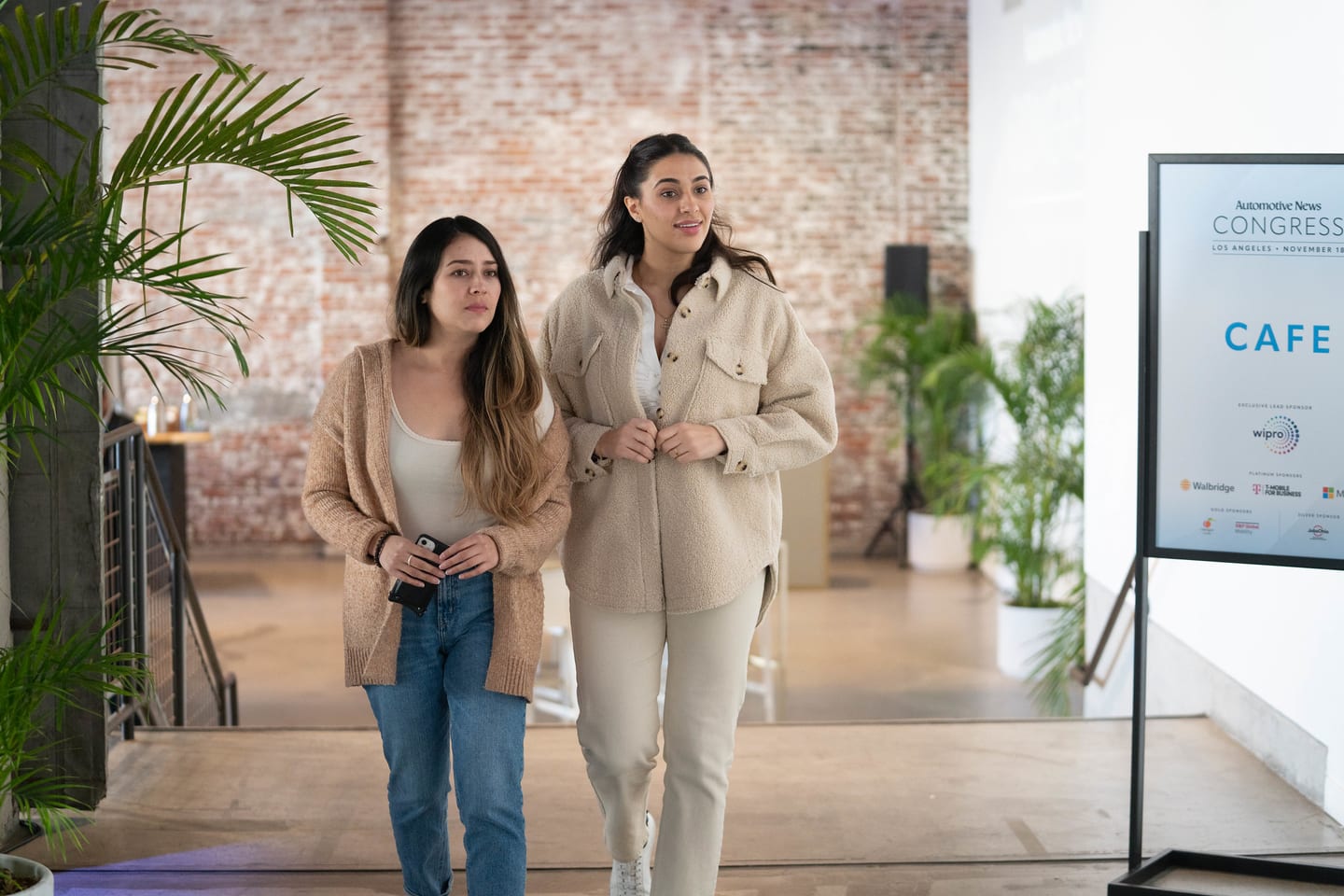 Two attendees walking in past the cafe signage as the morning begins at the Automotive News Congress: Los Angeles, City Market Social House