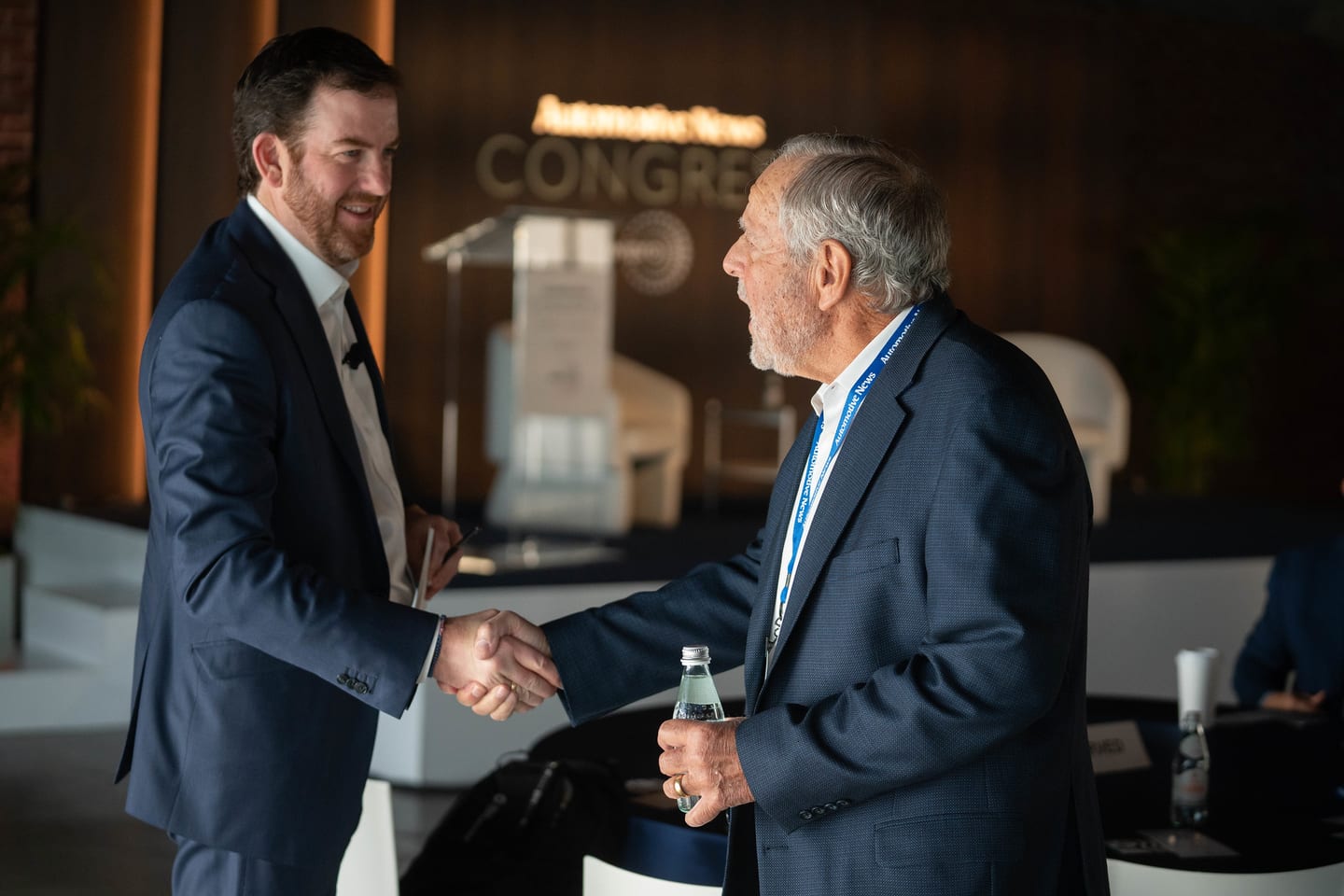Two attendees shaking hands in front of the Automotive News Congress stage at the Automotive News Congress: Los Angeles, City Market Social House