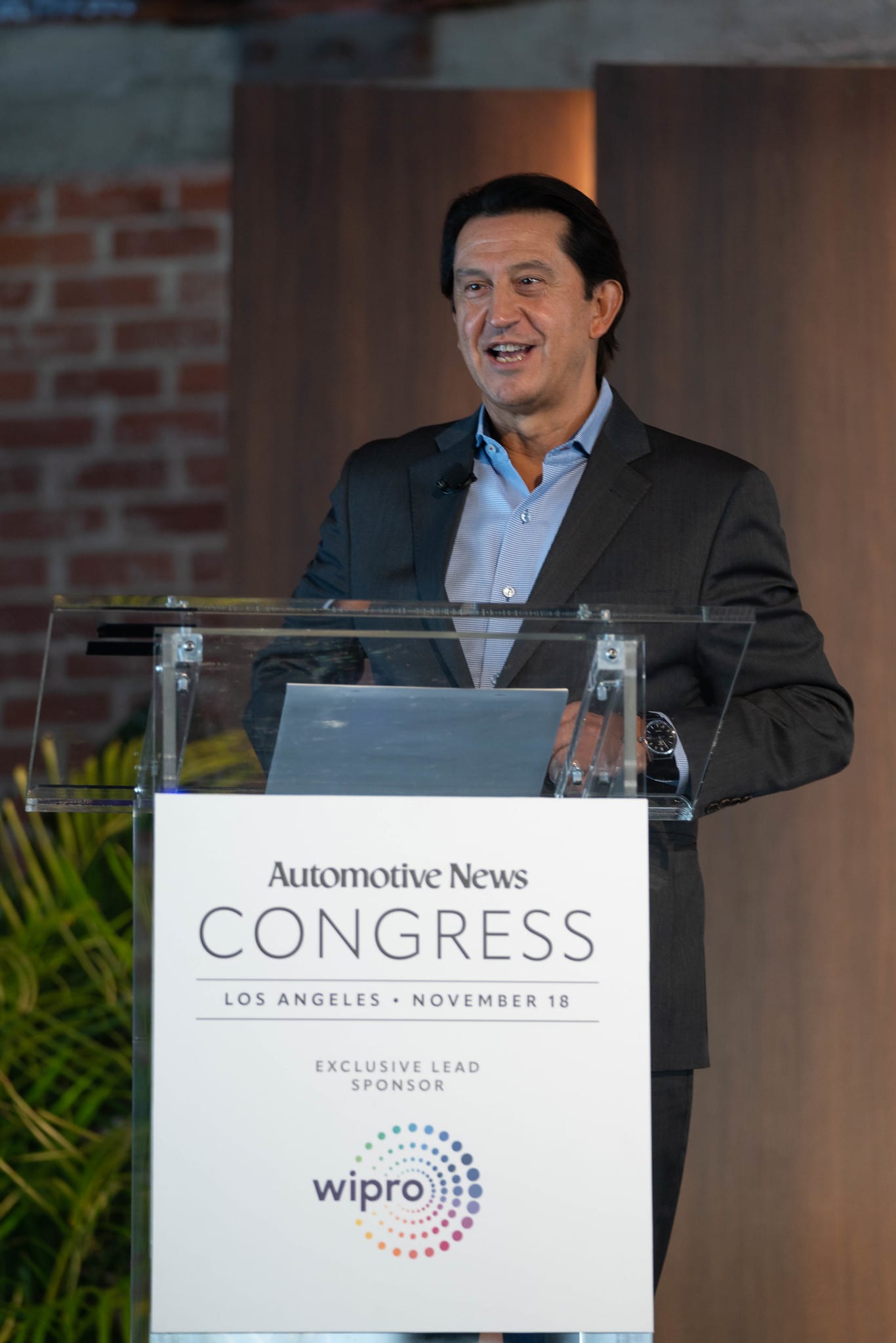 A speaker presenting at the Automotive News Congress lectern against the venue brick at the Automotive News Congress: Los Angeles, City Market Social House