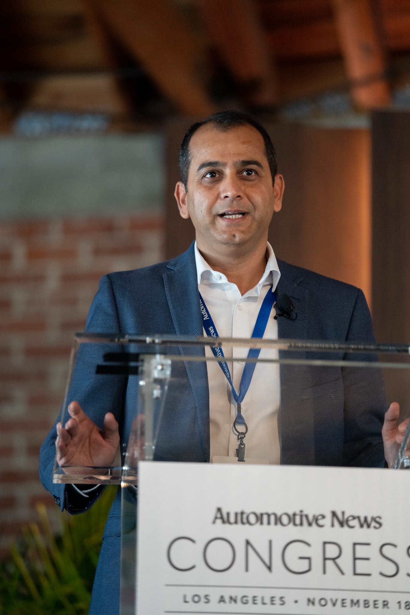 A speaker presenting at the Congress lectern against the venue’s brick wall at the Automotive News Congress: Los Angeles, City Market Social House