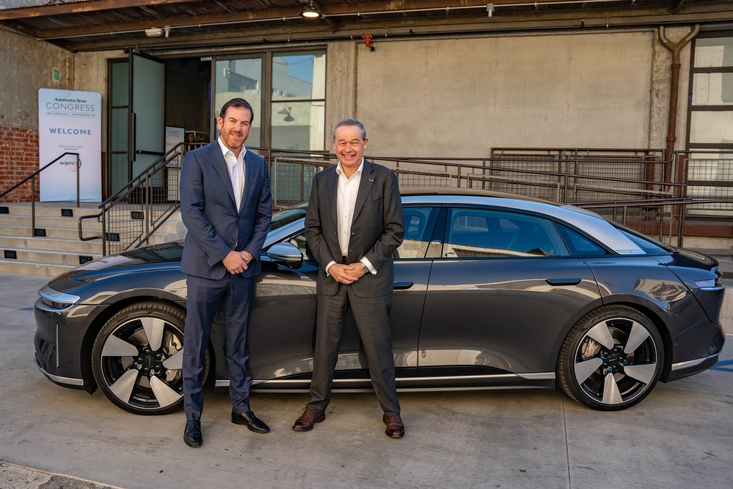 Two executives standing beside a Lucid Air electric sedan brought into the venue for the program at the Automotive News Congress: Los Angeles, City Market Social House