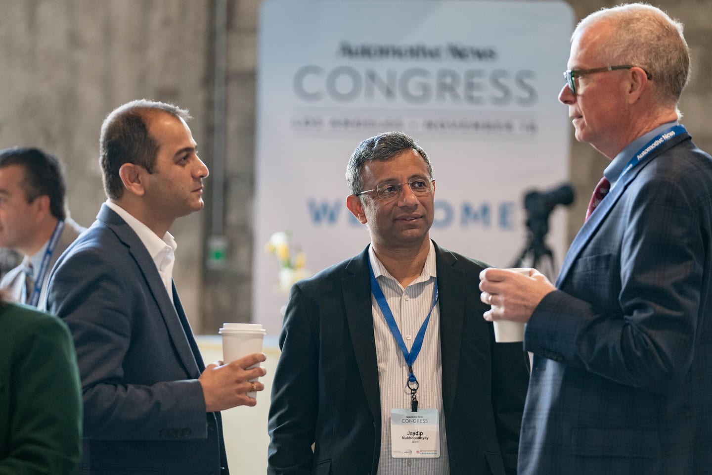 Attendees talking over coffee in front of the Congress backdrop during the morning networking at the Automotive News Congress: Los Angeles, City Market Social House
