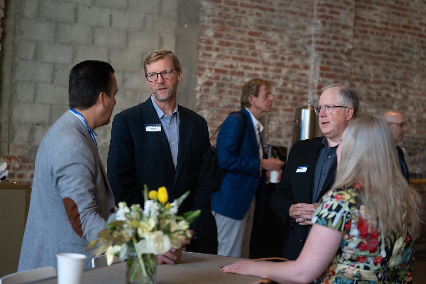 A group of attendees in conversation around a high table with flowers at the Automotive News Congress: Los Angeles, City Market Social House