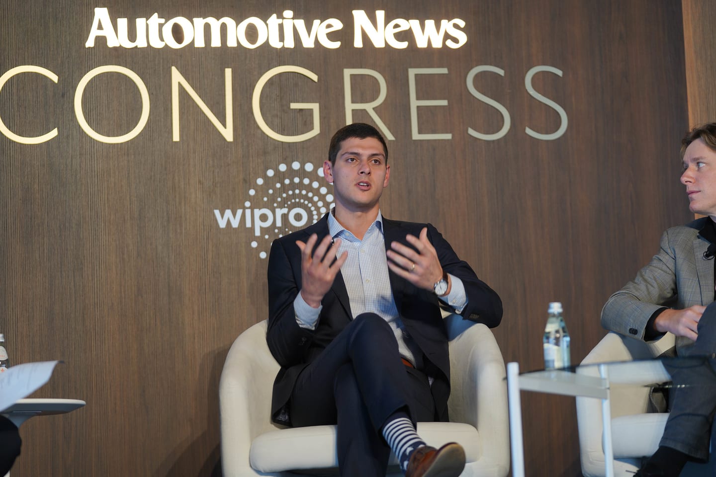 A panellist gesturing mid-answer in front of the Automotive News Congress and Wipro branding at the Automotive News Congress: Los Angeles, City Market Social House