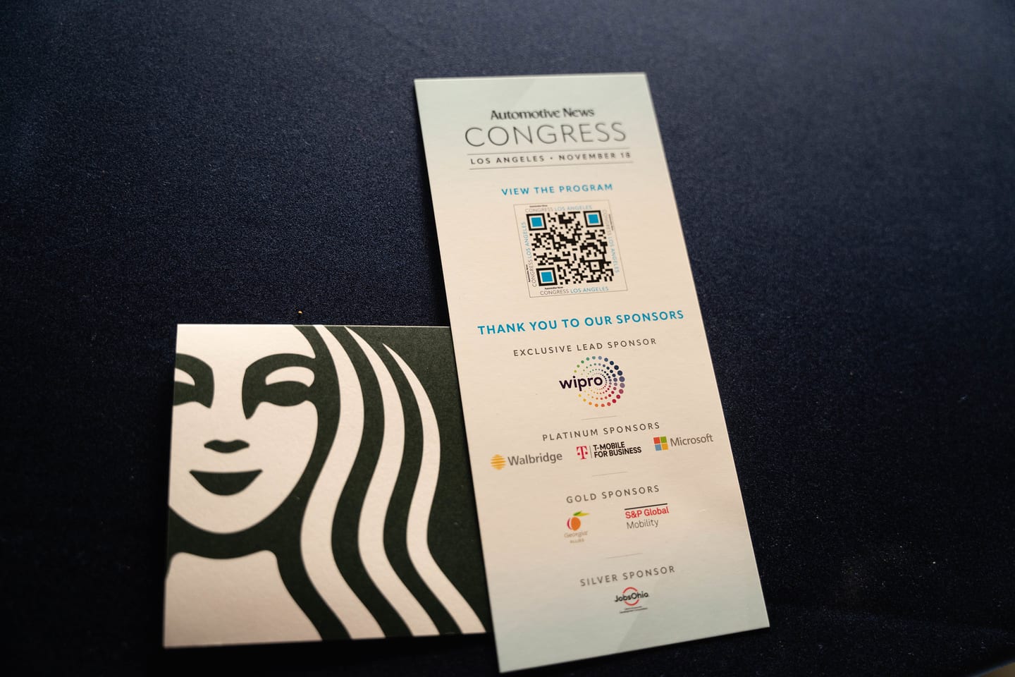 A printed Congress program card listing the event sponsors, on a table at the Automotive News Congress: Los Angeles, City Market Social House