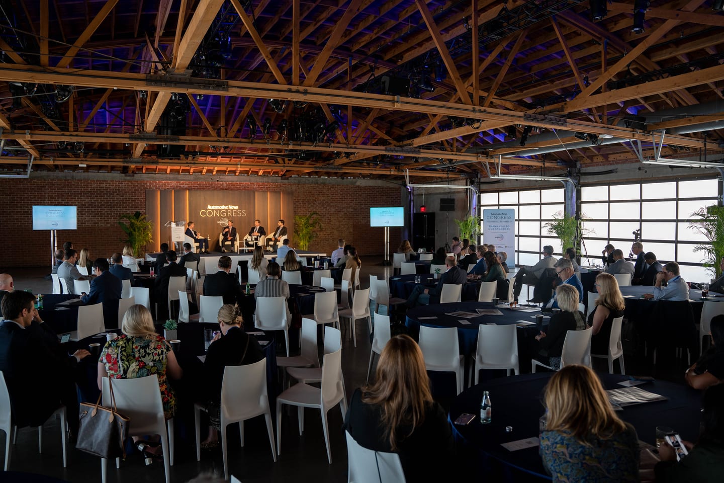 A wide view from the back of the room showing the full audience, the stage and the venue’s exposed timber trusses at the Automotive News Congress: Los Angeles, City Market Social House
