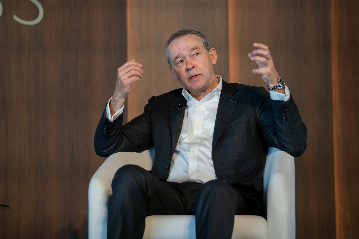 A speaker gesturing from a lounge chair during an on-stage interview at the Automotive News Congress: Los Angeles, City Market Social House