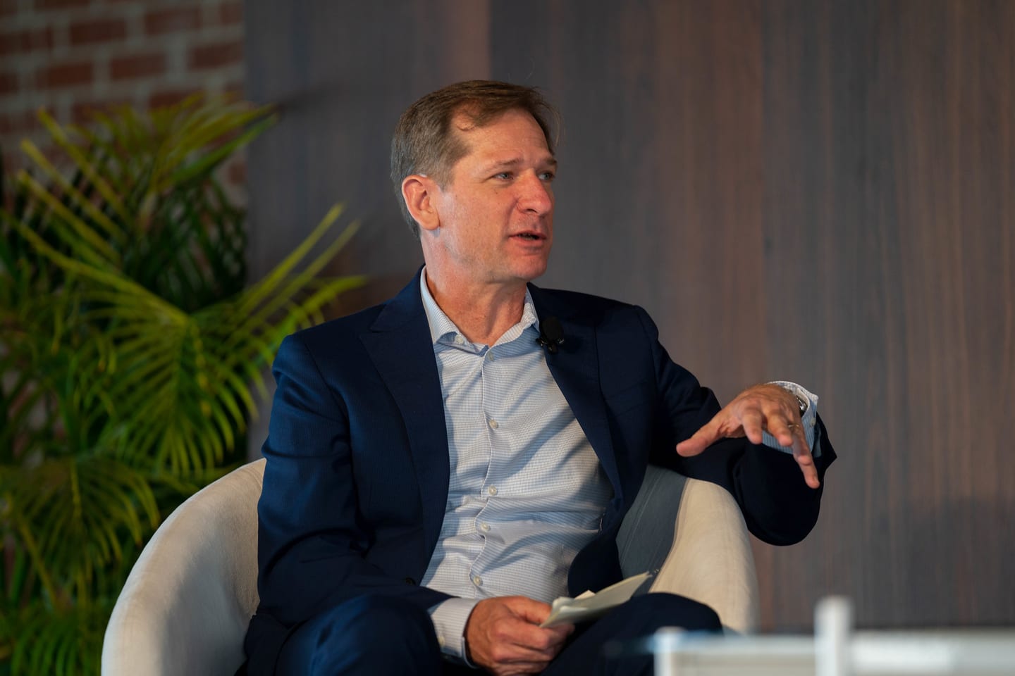 A speaker in a navy blazer gesturing during an on-stage conversation at the Automotive News Congress: Los Angeles, City Market Social House