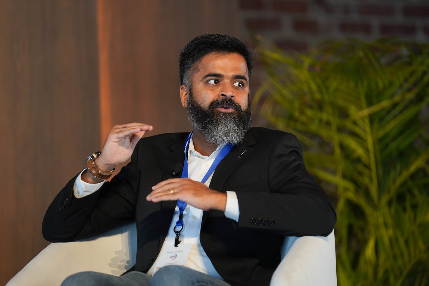 A seated panellist gesturing during a stage conversation at the Automotive News Congress: Los Angeles, City Market Social House
