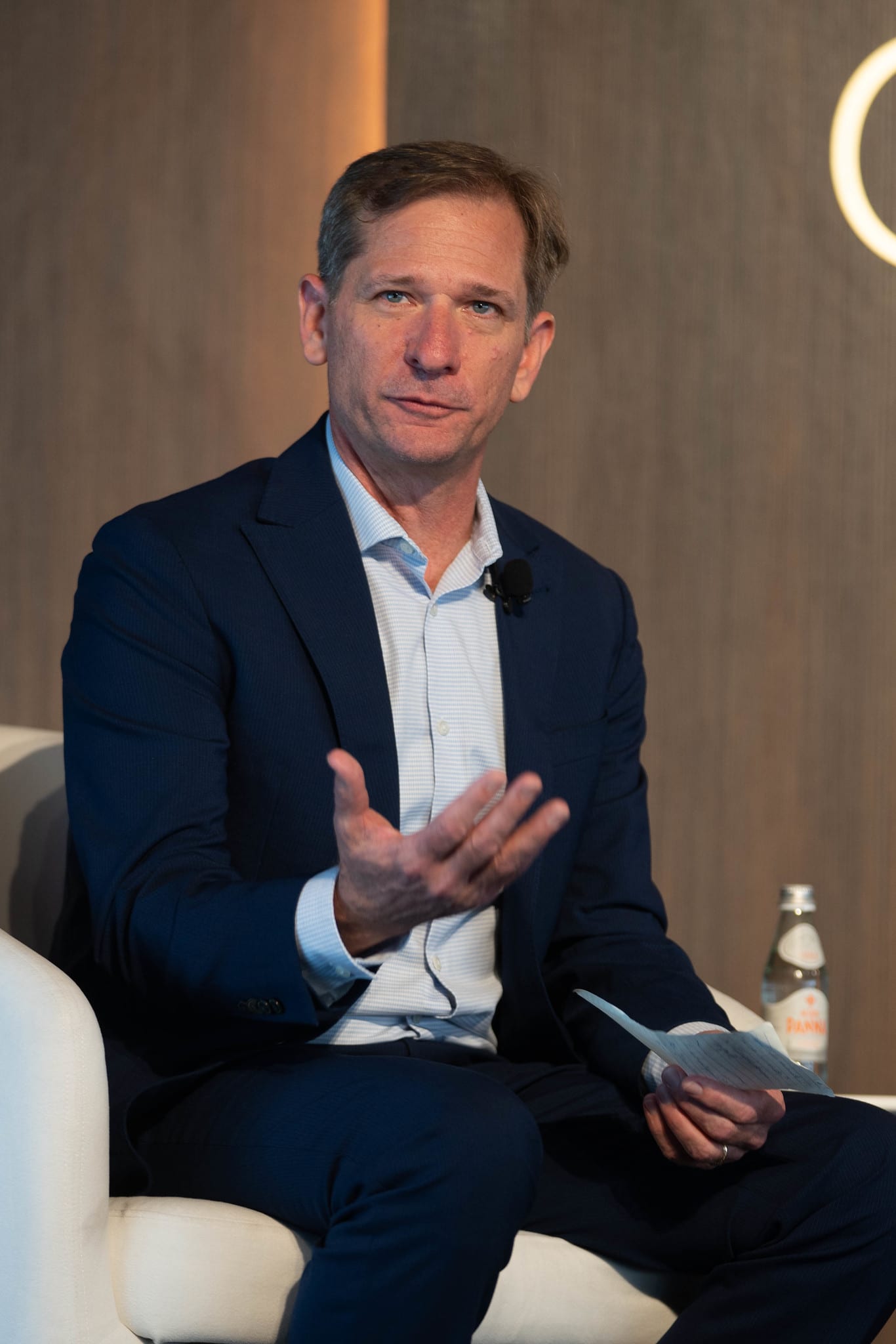 A speaker in a navy suit answering a question from a lounge chair on stage at the Automotive News Congress: Los Angeles, City Market Social House