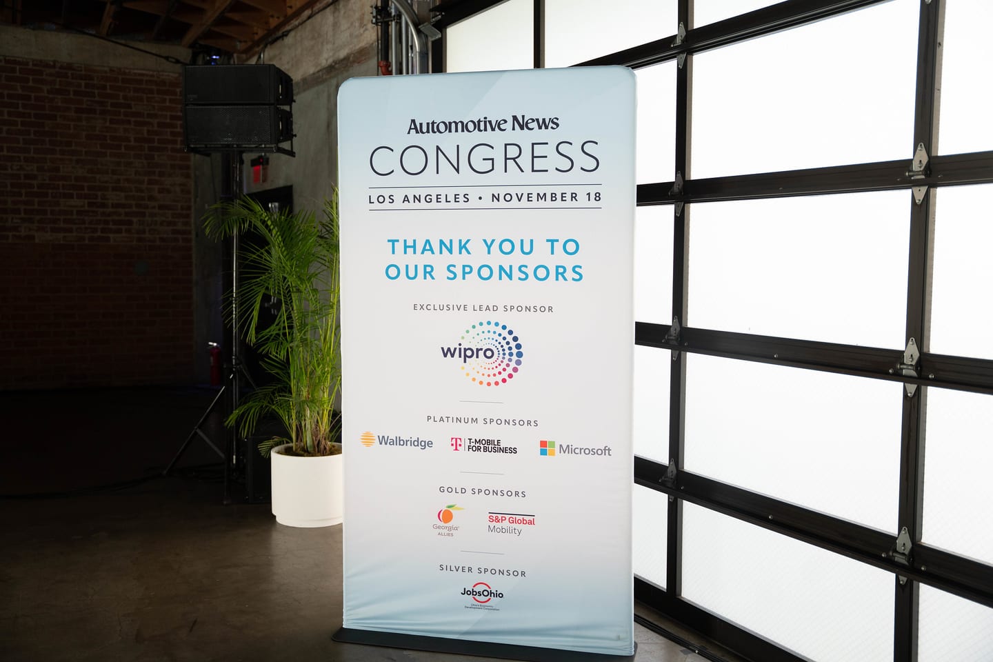 The sponsor thank-you banner standing against the venue’s industrial windows at the Automotive News Congress: Los Angeles, City Market Social House