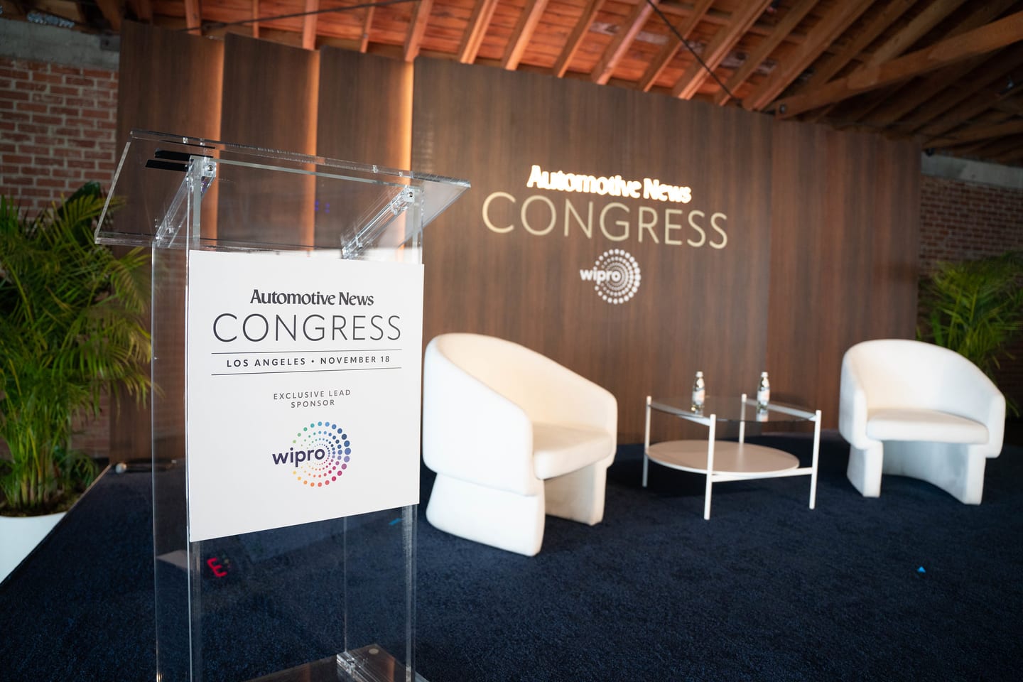 An empty stage set with a lectern, two lounge chairs and an Automotive News Congress Los Angeles November 18 sign, photographed before guests arrived at the Automotive News Congress: Los Angeles, City Market Social House