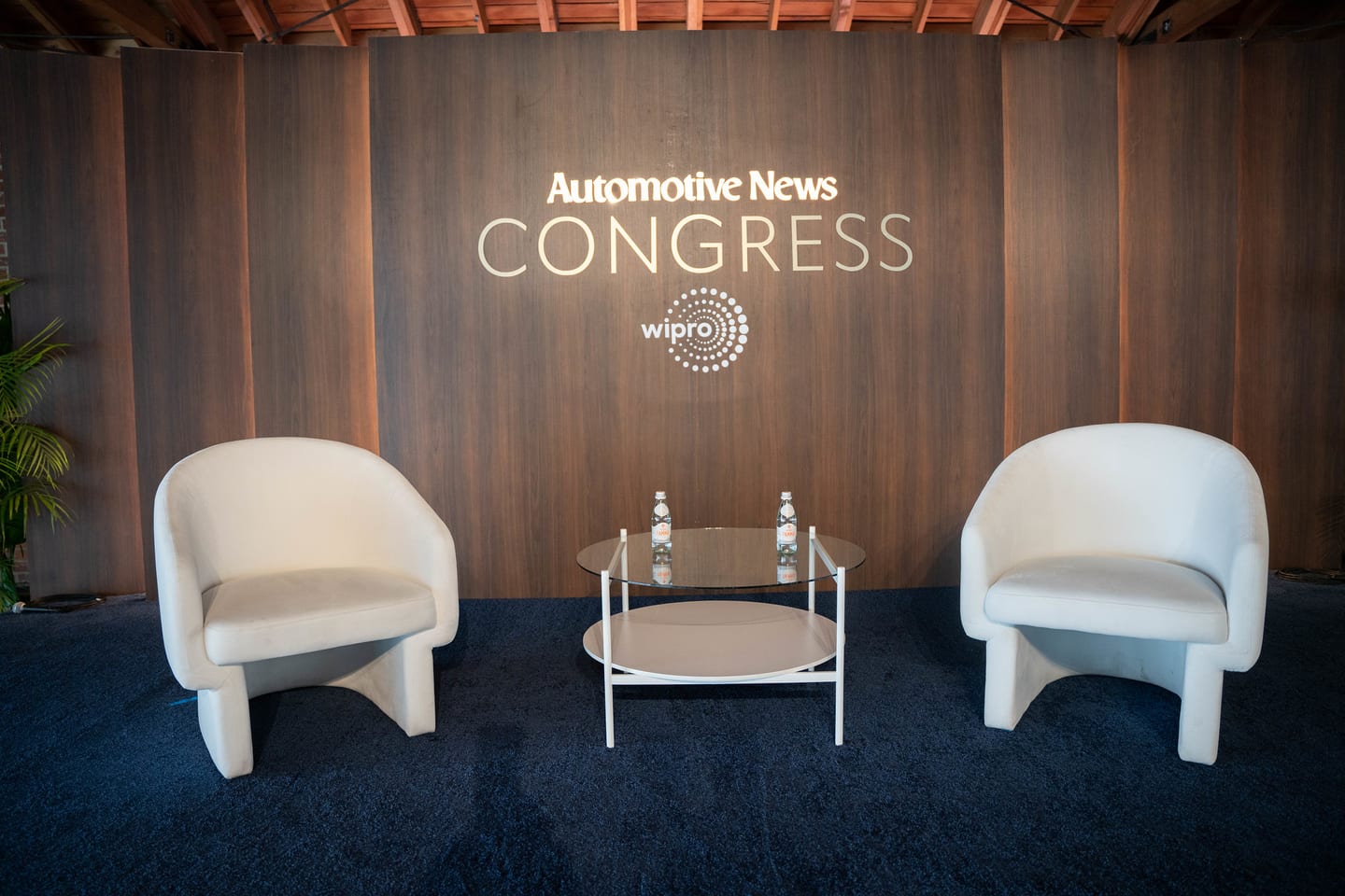 The empty stage set with two lounge chairs beneath the Automotive News Congress and Wipro branding at the Automotive News Congress: Los Angeles, City Market Social House