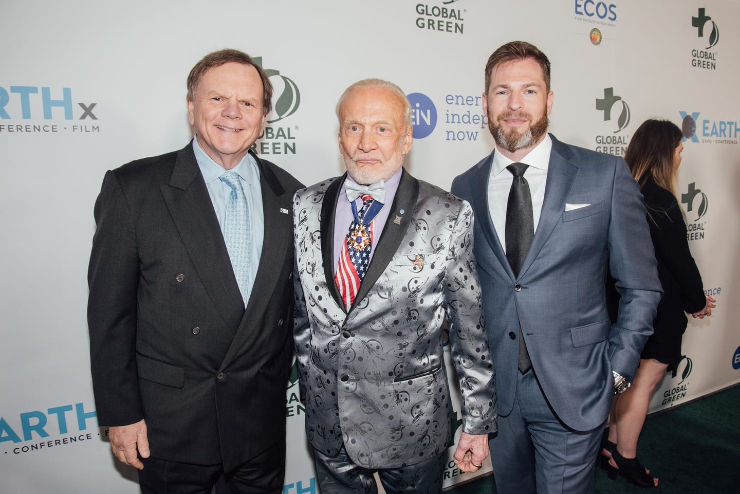 Former astronaut Buzz Aldrin in a silver jacket with two guests on the green carpet at the Global Green pre-Oscar gala