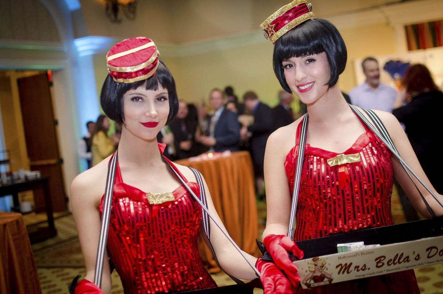 Two costumed hosts in red sequined cigarette-girl outfits at a brand activation