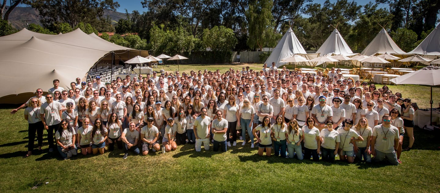 Large company team gathered for a group photo on a lawn at a corporate offsite