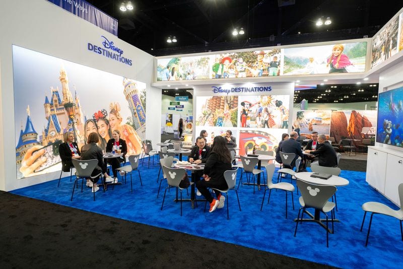 Buyers meeting at tables inside the Disney Destinations exhibitor booth at the IPW travel trade show